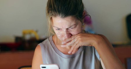 Foto de Mujer preocupada mirando la pantalla del teléfono celular mujer franca vida real preocupada leyendo información - Imagen libre de derechos