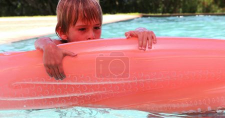Téléchargez les photos : Petit garçon à la piscine tenant dans le matelas gonflable - en image libre de droit