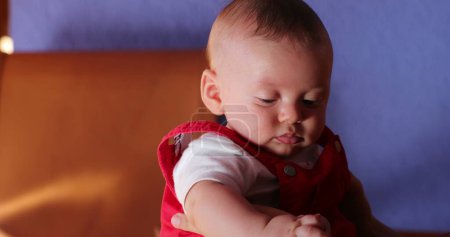 Foto de Holding baby boy portrait 4 month old infant with blue orange and red color contrast - Imagen libre de derechos