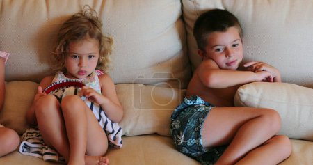 Téléchargez les photos : Enfants assis sur un canapé regardant un film - en image libre de droit