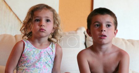 Foto de Lindo niño y niña viendo la pantalla de TV en casa - Imagen libre de derechos