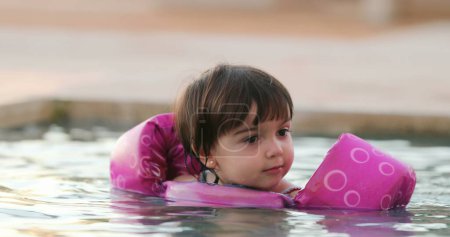 Photo for Little girl inside water with inflatable arms learning - Royalty Free Image