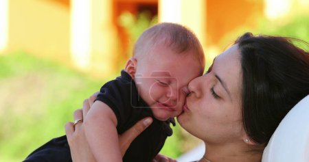 Foto de Mom calming crying baby infant outdoors showing love affection and care - Imagen libre de derechos