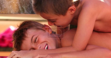 Foto de Momento divertido juntos entre hermanos un niño acostado encima de hermano comprimiendo cuerpo con peso - Imagen libre de derechos