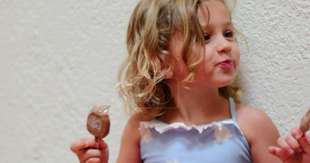 Téléchargez les photos : Candid small girl eating chocolate ice-cream - en image libre de droit