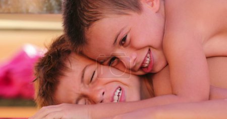 Photo for Brother bullying sibling lying on top of brothers body compressing with weight - Royalty Free Image