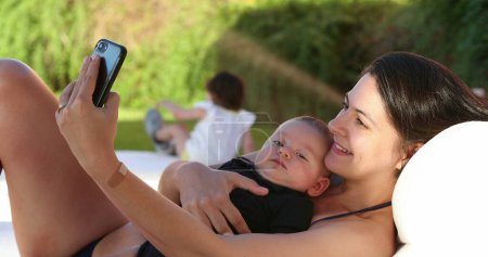 Photo for Mother taking selfie with her baby outdoors smiling posing for photo - Royalty Free Image
