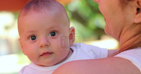 Foto de Infant newborn baby changing emotions outdoors held by mom - Imagen libre de derechos
