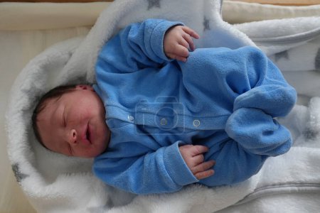 Eine detaillierte Nahaufnahme eines friedlichen neugeborenen Babys mit winzigen geschlossenen Augen und zarten Gesichtszügen, eingewickelt in eine weiche Decke, unterstreicht die Unschuld und Schönheit des neuen Lebens.