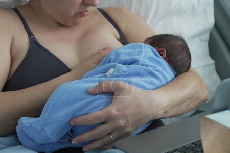 Foto de Una madre amamantando a su bebé recién nacido en una cama de hospital, mostrando los momentos tiernos y el fuerte vínculo entre la madre y el niño en un ambiente nutritivo. - Imagen libre de derechos