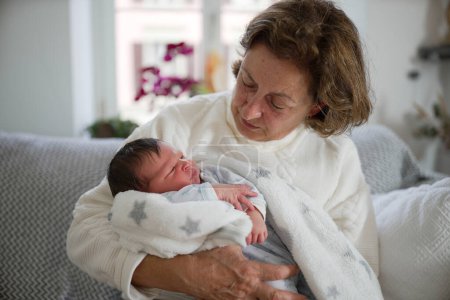 Téléchargez les photos : Mère tenant le nouveau-né par-dessus son épaule, debout près d'une fenêtre lumineuse. L'image saisit un moment tendre de liaison, soulignant le confort et la sécurité fournis par un parent aimant. - en image libre de droit