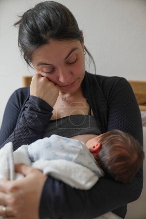 Mère fatiguée qui allaite son nouveau-né, les larmes aux yeux, incarnant les défis émotionnels et physiques de la maternité précoce. Ce moment met en lumière la lutte et la force des nouvelles mères