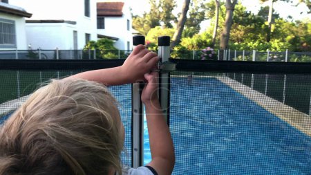 Téléchargez les photos : Enfant souhaitant ouvrir un portail de protection de piscine - en image libre de droit
