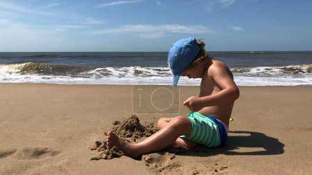Foto de Niño jugando con arena en la playa - Imagen libre de derechos