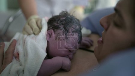 Newborn baby crying for the first time right after birth resting on mother's chest, mother and infant's first seconds of life together, maternal care concept bringing a human being to life