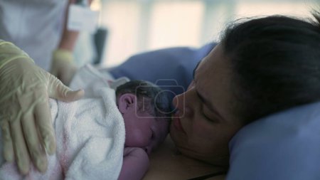 Nurse's hand trying to make newborn baby cry right after birth, infant's first seconds of life resting on mother's chest during childbirth moment, birthing of new life