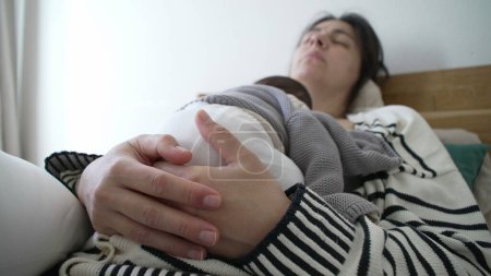 Großaufnahme der Hände der Mutter, die das Neugeborene schlafend auf der Brust hält, Eltern und Kind im Tiefschlaf während der Anfangsphase der Mutterschaft, der ersten Woche im Leben des Säuglings