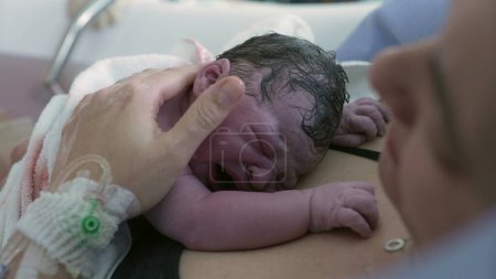 Mother welcoming her newborn baby after giving birth, infant crying on mother's chest after childbirth, initial cries, first seconds of life at hospital