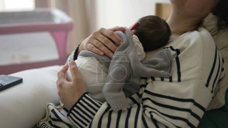 Mother holding newborn baby on chest while taking a nap, woman laid in bed holding infant tight on chest during initial week of life, maternal care affectionate lifestyle scene