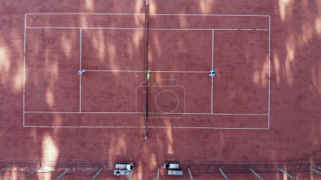 Tennis court seen from above in vertical shot. Two people practicing tennis