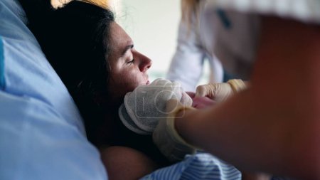 Mother Trembling with Pain After Giving Birth, Surrounded by Caring Medical Team in Maternity Clinic, as Newborn is Gently Placed on Her Chest