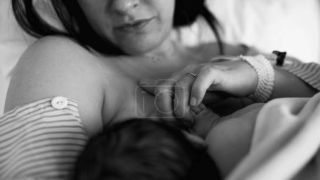 Monochrome moment of new mother breastfeeding her newborn baby after childbirth in black and white at hospital