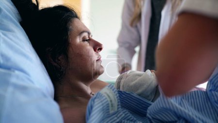 Mother Trembling with Pain After Giving Birth, Surrounded by Caring Medical Team in Maternity Clinic, as Newborn is Gently Placed on Her Chest