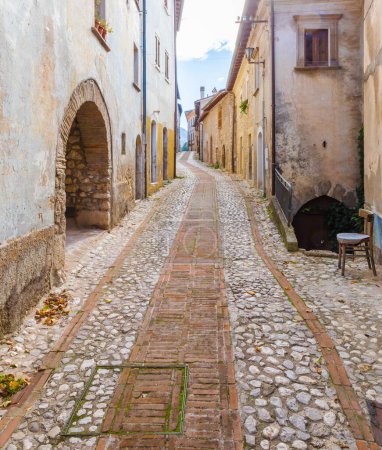 Photo for Alley with cobblestones and an empty chair among the ancient houses in the village of Petrella Salto in the province of Rieti. Italy. - Royalty Free Image