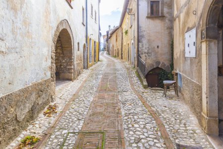 Photo for Alley with cobblestones and an empty chair among the ancient houses in the village of Petrella Salto in the province of Rieti. Italy. - Royalty Free Image