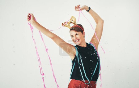 This has always been my favorite time of the year. an attractive and cheerful young woman celebrating with confetti falling around her against a grey background