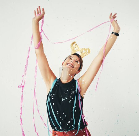 The festive spirit has taken over. an attractive and cheerful young woman celebrating with confetti falling around her against a grey background
