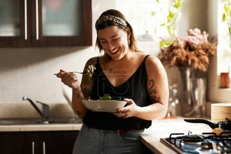 Ist es wirklich eine Diät, wenn sie so gut schmeckt? eine junge Frau isst zu Hause einen gesunden Salat