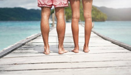 Foto de Ponte de pie y mantente orgulloso. Vista trasera de una pareja irreconocible de pie en un paseo marítimo con vistas al océano durante unas vacaciones - Imagen libre de derechos