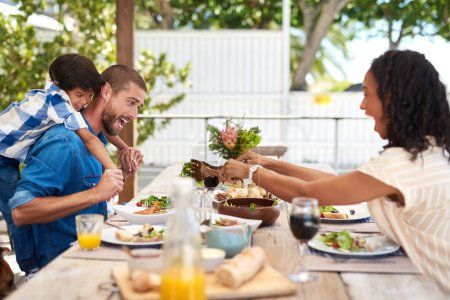 Téléchargez les photos : Prenez toujours du temps pour votre famille. une belle jeune famille qui s'amuse tout en prenant un repas ensemble autour d'une table à l'extérieur - en image libre de droit