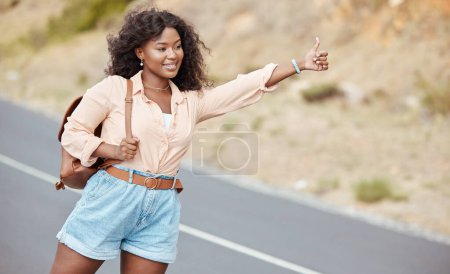 Black woman, travel and thumbs up on the road for lift in nature for assistance, help or trip in the outdoors. African American female traveler or hitch hiker with roadside hand gesture for transport.