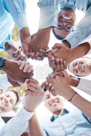 Low angle, business people and holding hands in support circle, community partnership or team building motivation. Smile, happy or teamwork diversity in trust, collaboration or growth mission success.