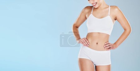 Foto de Salud, cuerpo y maqueta con un modelo de mujeres en ropa interior en un fondo azul en el estudio para promover la pérdida de peso. Fitness, bienestar y dieta con una mujer feliz posando para un estilo de vida saludable. - Imagen libre de derechos