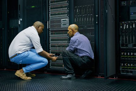 Trabajar eficientemente para resolver el problema. dos técnicos de TI que reparan una computadora en un centro de datos