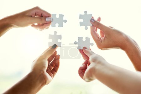 Photo for Its a perfect fit. Closeup shot of four unrecognizable people joining puzzle pieces together - Royalty Free Image