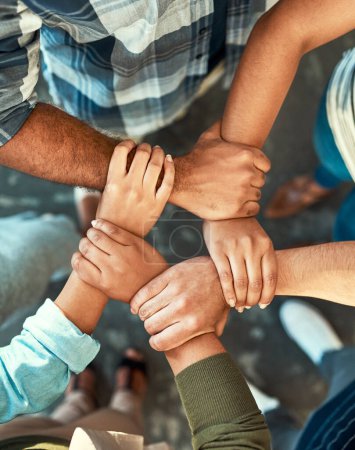 Photo for Hand together we can do this no matter what. High angle shot of a young group of work colleagues forming an unique huddle with their arms and hands while standing in the office at work - Royalty Free Image