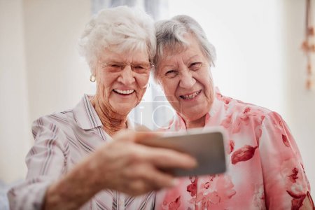 Photo for Retirement - time to enjoy yourselfie. Portrait of two happy elderly women taking selfies together on a mobile phone - Royalty Free Image