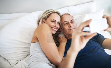 Foto de Nos tomamos unos selfies increíbles juntos. una pareja madura cariñosa tomando selfies en la cama juntos en casa - Imagen libre de derechos