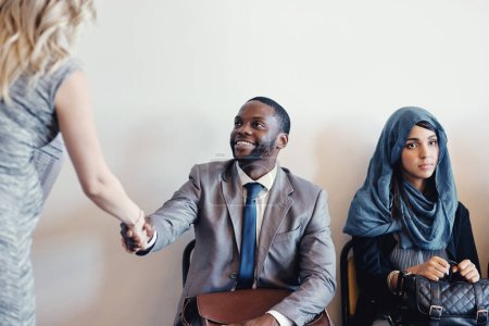 Photo for Glad that you can join us. a cheerful young business receiving a handshake from a businesswoman while waiting for a interview inside of a office during the day - Royalty Free Image