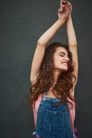 Getting some stretching in for the day. a carefree young woman raising her arms and stretching while standing against a grey background