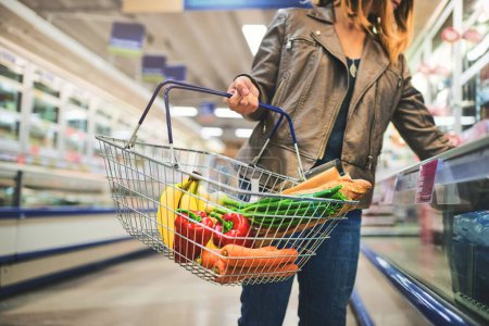 Photo for With that quality its no wonder she shops here. a woman holding a basket while shopping at a grocery store - Royalty Free Image