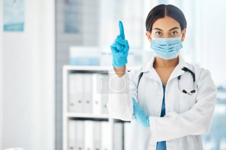 Woman, pointing doctor and covid face mask in hospital, clinic or wellness pharmacy for global virus stop, compliance or rules. Portrait, healthcare worker or medical employee with advertising space.