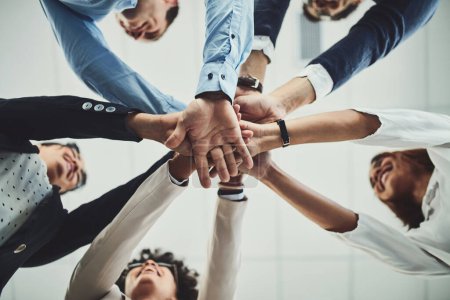 Photo for Here we go guys. Low angle shot of a group of businesspeople forming a huddle with their hands inside of the office during the day - Royalty Free Image