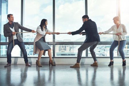 Photo for The business world is quite a competitive one. a group of businesspeople pulling on a rope during tug of war in an office - Royalty Free Image
