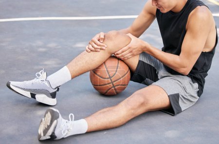 Téléchargez les photos : Basket-ball, l'homme et le genou dans les blessures sportives sur le terrain tenant douloureux, douloureux ou tendre zone en plein air. Joueur de basket-ball souffrant de douleurs aux jambes, d'articulations ou d'inflammation dans un match ou un jeu sportif. - en image libre de droit