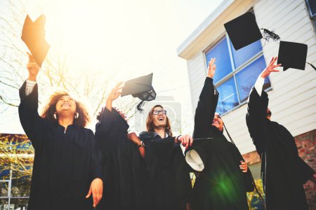 Foto de Celebrando nuestros esfuerzos. un grupo de estudiantes lanzando sus gorras al aire después de graduarse - Imagen libre de derechos
